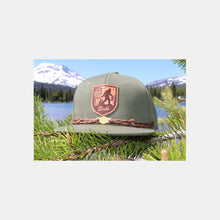 Load image into Gallery viewer, Olive snapback hat w/ tan/brown leather patch w/ Sasquatch carrying DDIR bag. Tan laces &amp; wooden &quot;Dick&#39;s&quot; cloud logo clip
